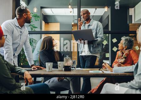 Diverse business professionals having a discussion during a meeting in a modern office. Team of multicultural businesspeople sharing creative ideas in Stock Photo