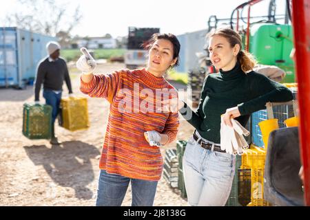 Positive women farmers discussing current issues in farm backyard Stock Photo