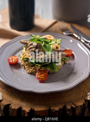 Beef stroganoff cooked in a creamy sauce, with quinoa, cherry tomatoes, basil leaves on a gray ceramic plate on a wooden board. Low calorie portion. B Stock Photo