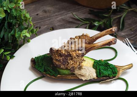 Rack of lamb in nut batter with baked vegetables. Spinach paste and baked eggplant. Molecular food. Stock Photo