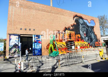 An artist painting a King Kong graffiti on on old brick factory building ( Joy Art building ) in the 798 Art Zone in Beijing, China. Stock Photo