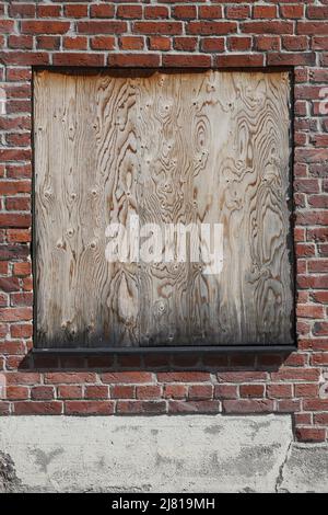 Close-up view of a plywood board that replaces the glass in the window in an old industrial building. Stock Photo