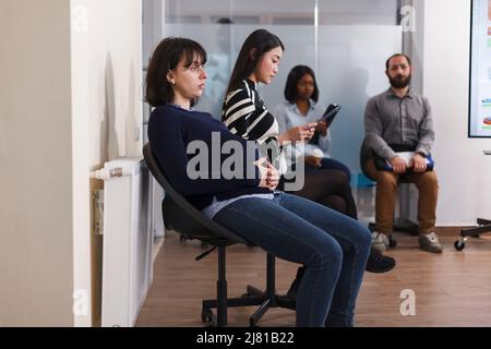 Diverse people waiting in queue office during company job interview holding recruitment files preparing for hiring meeting. Multiethnic group of candidates recruiting for business career opportunity Stock Photo