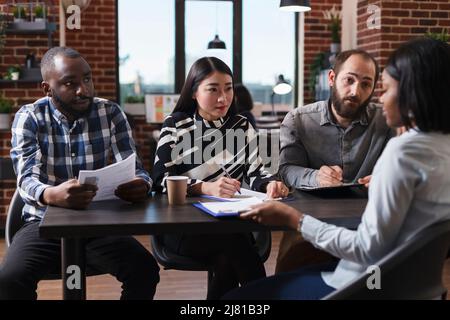 Diverse businesspeople interviewing african american candidate discussing cv resume recruiting employer for human resources job in startup company office. Concept of hiring process Stock Photo