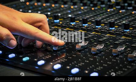 Male hand adjusting the volume on the sound mixing panel Stock Photo
