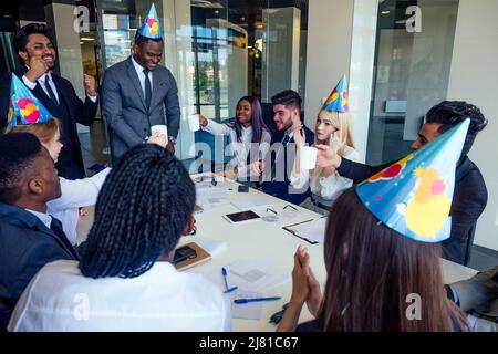 celebration international multi-cultural wear party hat businesswoman congratulations promotion of work. birthday boy hold knife cutting cake in a Stock Photo
