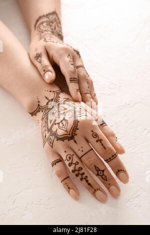 Female hands with beautiful henna tattoo on light background, closeup Stock Photo