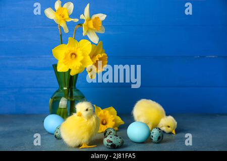 Cute chickens, Easter eggs and flowers on table Stock Photo