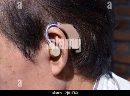 Electronic hearing aid device in the ear of Asian old man with total deafness. Stock Photo