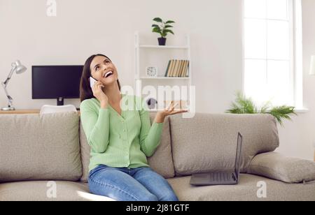 Cheerful woman using smartphone laughing gossiping and discussing news with her friend. Stock Photo