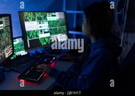 Young woman hacker by computer in the dark room at night, cyberwar concept. Stock Photo