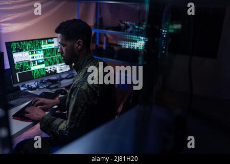 Hacker in military unifrorm on dark web, cyberwar concept. Stock Photo