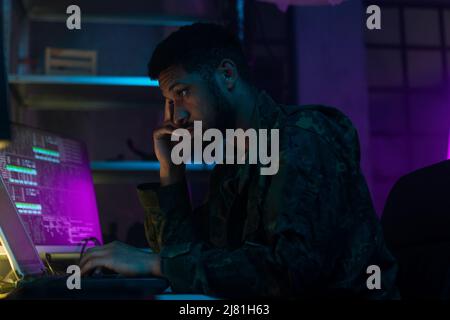 Hacker in military unifrorm on dark web, cyberwar concept. Stock Photo