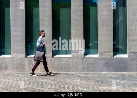 Young urban businessman professional walking in street wearing smart casual jacket. City lifestyle commute person walking. Stock Photo