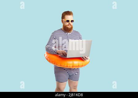 Funny fat businessman working on his laptop computer during summer holiday at beach Stock Photo