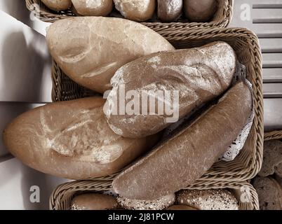 Delicious buns are on the table in a wicker basket. Top view, close-up. Stock Photo