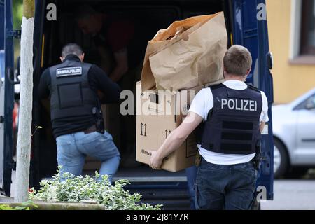 Essen, Germany. 12th May, 2022. Police officers carry objects from the suspect's home. Police in Essen are investigating a 16-year-old for possibly planning crimes at two schools. 'We can confirm that the suspect is a 16-year-old German student of the Don Bosco High School,' police wrote on Twitter. A police spokeswoman told Deutsche Presse-Agentur that an SEK squad searched the high school student's apartment early this morning. Credit: David Young/dpa/Alamy Live News Stock Photo