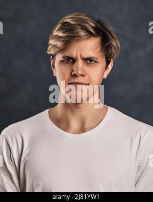 young man frowning on gray background. Human emotions Stock Photo