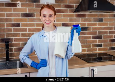 caucasian smiling redhaired woman working in kitchen in casual clothes and rubber gloves Stock Photo