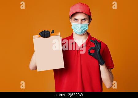 Delivery man employee in red cap face mask, empty cardboard box Stock Photo