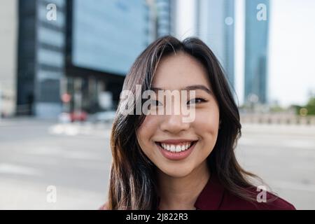 Asian business woman working outside of the office with city in background - Focus on face Stock Photo
