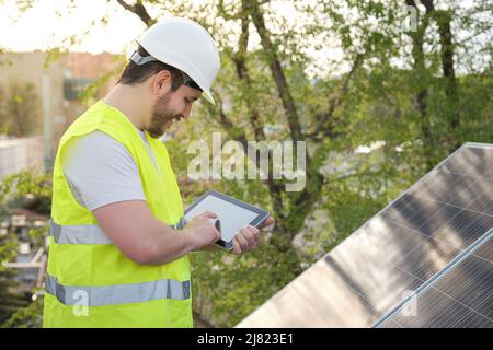 Technician using tablet for controlling photovoltaic solar power station. Stock Photo