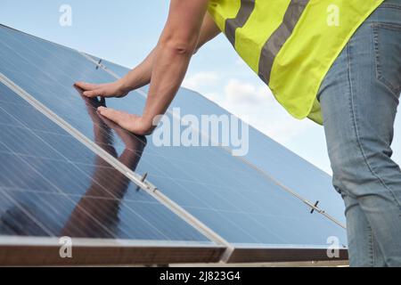 Close up of engineer checking operation and cleanliness of photovoltaic station. Stock Photo