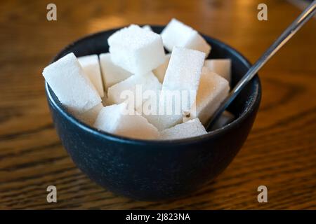 White sand sugar in wooden bowl and wooden spoon and cube sugar on wood table background. Stock Photo