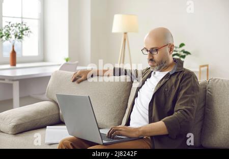 Middle-aged man work online on computer at home Stock Photo