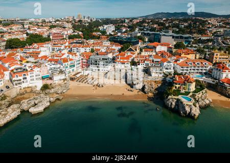 Drone aerial view of unidentifiable sunbathers at Praia da Rainha beach in Cascais, Portugal, a popular summer vacation spot for tourists Stock Photo