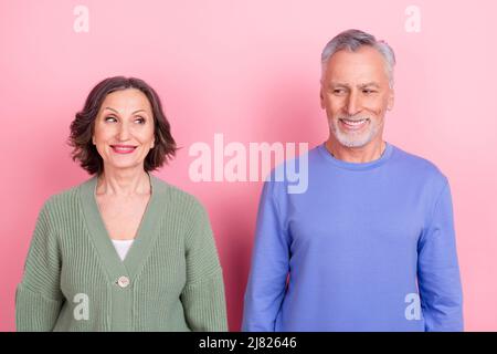 Portrait of two handsome beautiful curious shy people meeting first time isolated over pink pastel color background Stock Photo