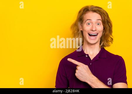 Photo of impressed millennial ginger guy indicate promo wear purple polo isolated on yellow color background Stock Photo