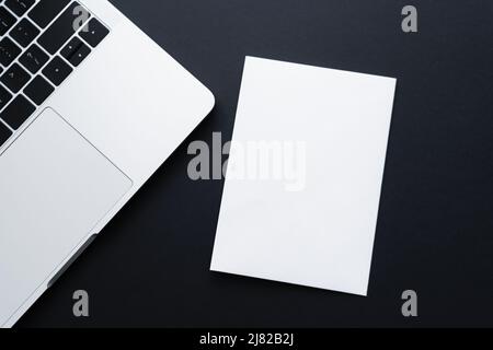 top view of blank paper near laptop on black Stock Photo