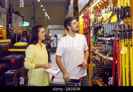 Happy married couple chooses variety of tools and materials for repairs in apartment. Stock Photo