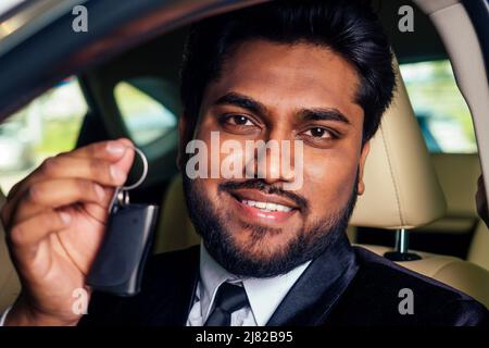 indian cheerful car salesman showing new keys showroom Stock Photo