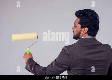 Young businessman with paint brush in hand on white background in studio copy space Stock Photo