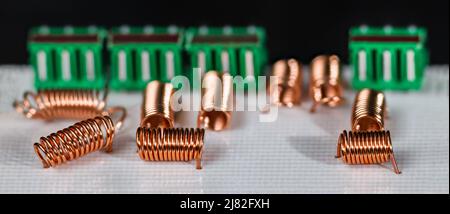 Orange radio-frequency inductors or green connectors in white PCB on black background. Copper wire winding of air core coils. Electronic circuit board. Stock Photo