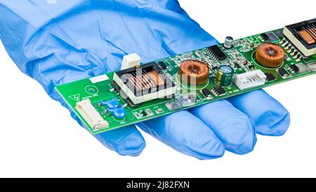 Toroidal coils and rectangular transformers on PCB detail isolated on white background. Closeup of inductors on printed circuit board in engineer hand. Stock Photo