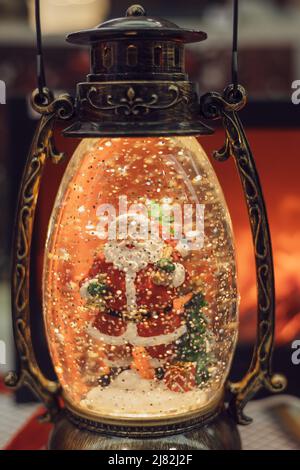 Decorative Christmas glass lantern with Santa figure inside. Elegant festive interior decoration. Stock Photo