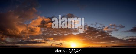 A sunset sky panorama with red and orange colors over the ocean Stock Photo