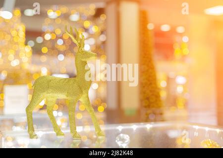 A Golden Shiny Christmas Deer Stands On A Glass Surface In Bright Bokeh 