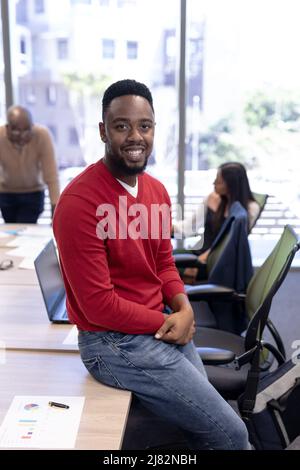 Portrait of smiling african american businessman leaning on conference table in boardroom Stock Photo