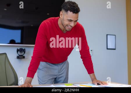 Happy hispanic young male advisor leaning on desk working at modern workplace Stock Photo