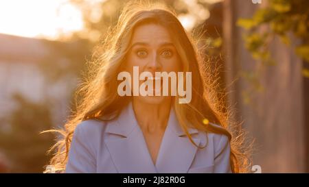 Portrait in sunlight sunset sun happy surprised delighted ecstatic shocked caucasian girl woman covers mouth with hands from surprise shock delight Stock Photo