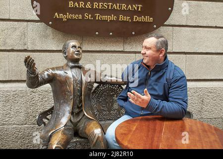 Bronze statues of Oliver Saint John Gogarty and James Joyce outside the pub of the same name in Temple Bar Dublin, Ireland with tourist man Stock Photo