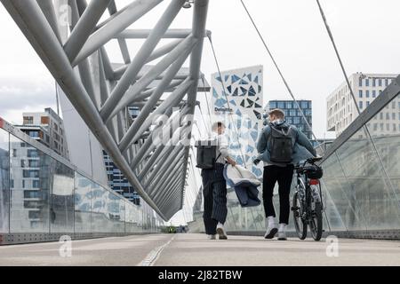 Oslo, Norway. May 02, 2022: Modern pedestrian bridge in Oslo, Norway. View of urban architecture. Walking people with bicycle. Stock Photo