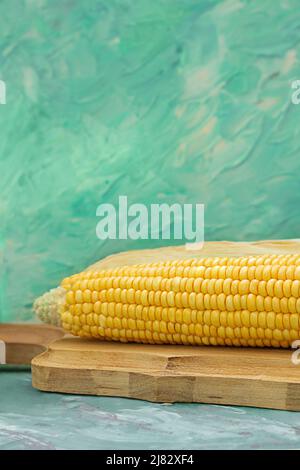 Yellow raw corn in husk on wooden cutting board. Back watercolor background. food, vegetarianism. Vertical. Copy space Stock Photo