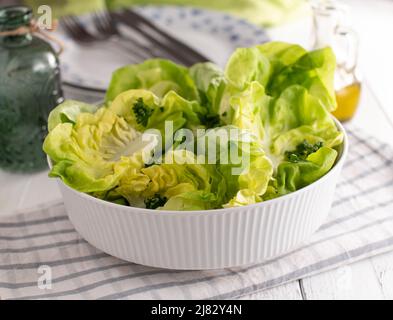 Fresh green salad in a bowl with lettuce . Served for side dish on white kitchen table Stock Photo