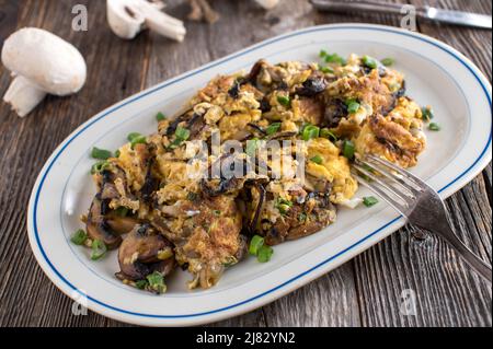 Scrambled eggs with mushrooms and onions on plate with fork. Stock Photo