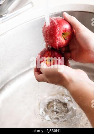 Red Apple being washed in the sink Stock Photo